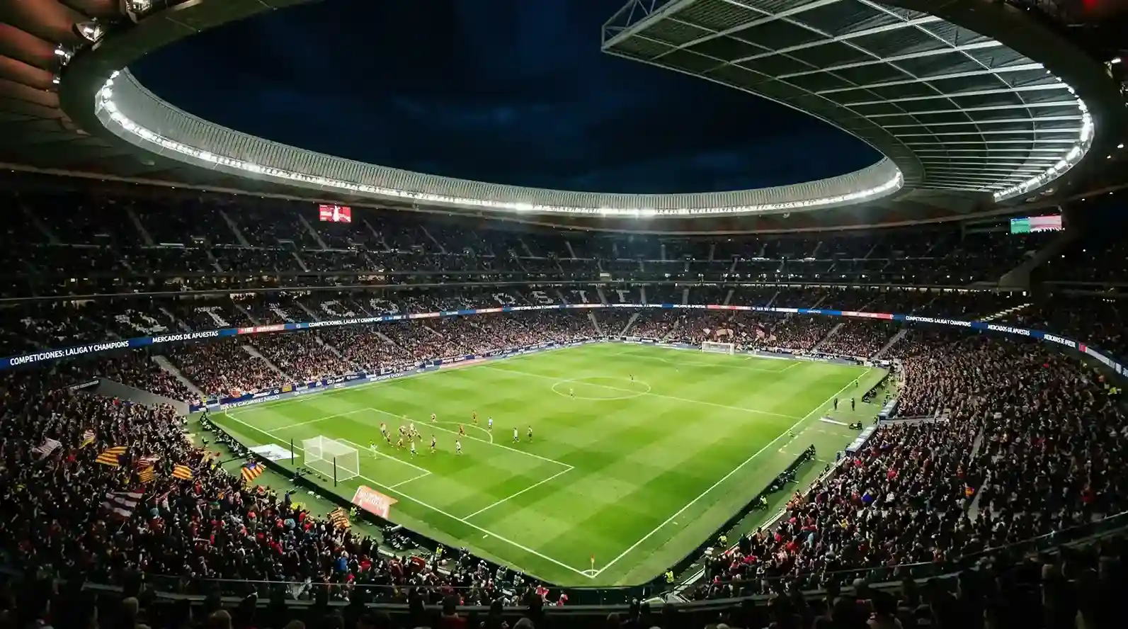Estadio de fútbol profesional iluminado durante un partido nocturno de LaLiga con las gradas llenas